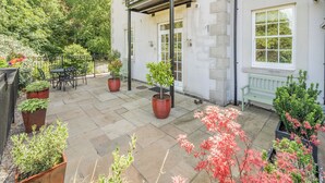 A courtyard with a balcony, potted plants, and outdoor furniture. - Apartment 14, Hazelwood Hall (Silverdale, near Arnside)