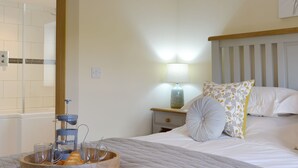 A bedroom with a bed, bedside table, lamp, and a view of the bathroom. - Swift Cottage - UKC3435 (East Ogwell, near Newton Abbot)