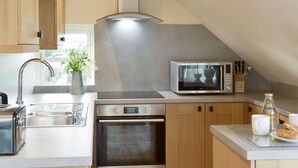 A modern kitchen with a built-in oven, microwave, and stainless steel appliances. - Swift Cottage - UKC3435 (East Ogwell, near Newton Abbot)