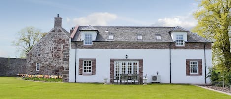 A two-story stone and plaster building with a lawn in front.