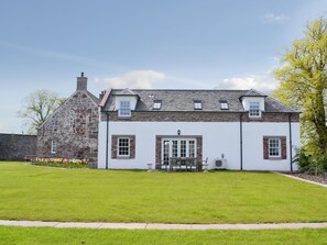 A two-story stone and plaster building with a lawn in front.