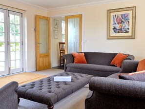 Ein Wohnzimmer mit grauem Sofa, passendem Hocker und einer Holztür.