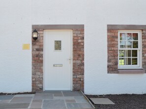 A white door with a small window above it, a light fixture to the left, and a brick wall. - The Old Gasworks Building (Montrose)