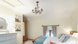 A bedroom with a bed, bedside table, dresser, and a chandelier. - Horseshoe House - UKC2743 (Saham Toney, near Thetford)