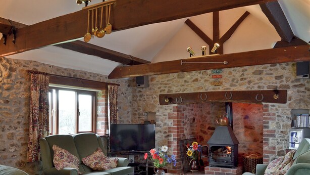 A cozy living room with a stone fireplace, a television, and comfortable seating.