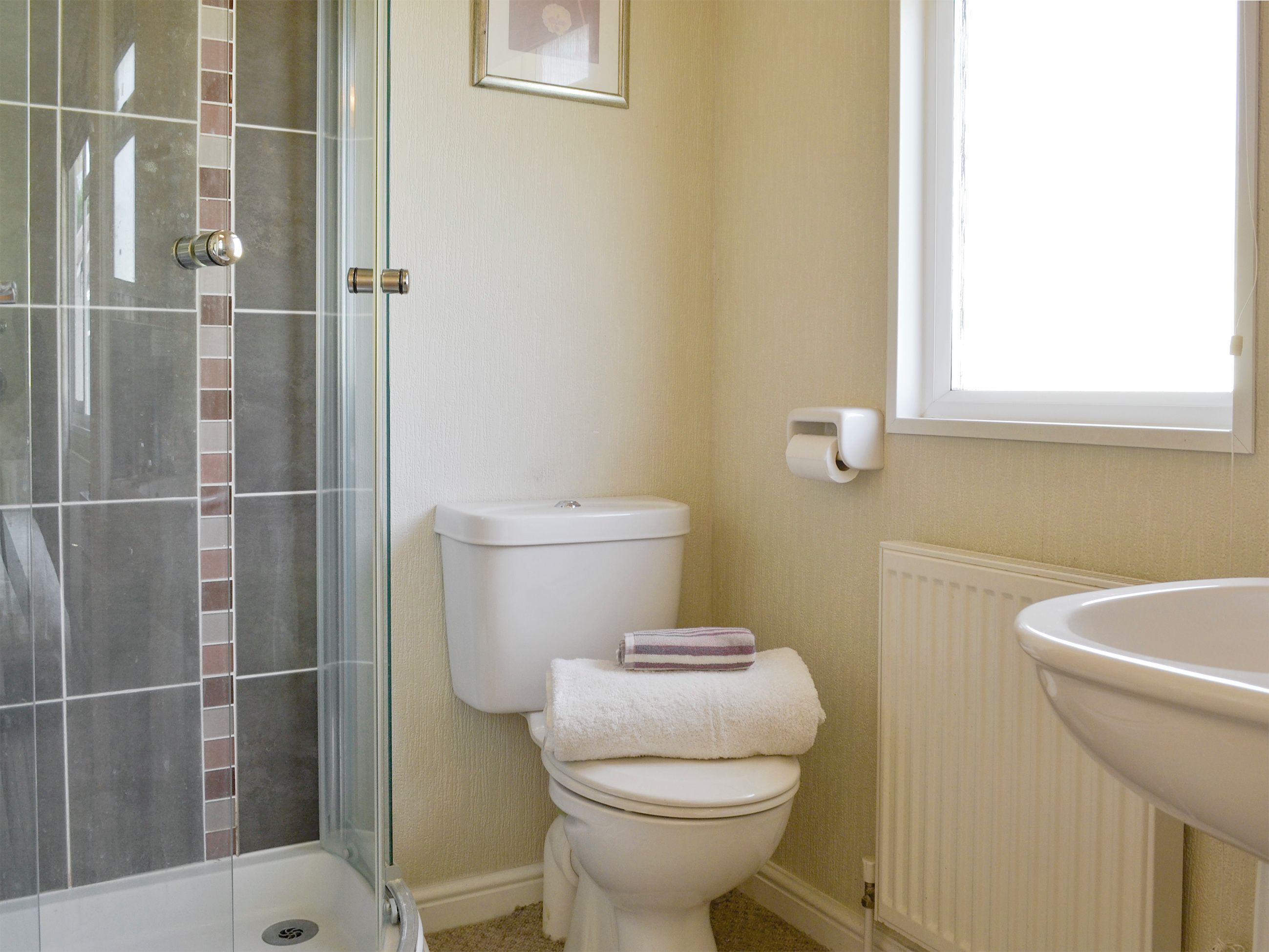 Un bagno con cabina doccia in vetro, un water e un lavandino.