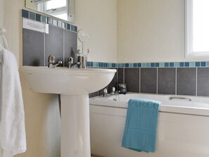 A bathroom with a white sink, a bathtub, and a blue towel hanging on the wall. - 2 bedroom accommodation in Woodacott, near Holsworthy (Woodacott, near Holsworthy)