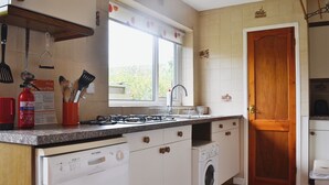Ett kök med en gasspis, en tvättmaskin och ett handfat.