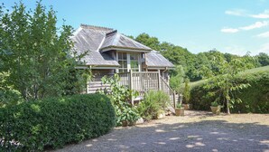 A rustic house with a sloped roof, wooden porch, and a gravel driveway.