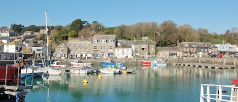 A harbor with boats docked, buildings along the shore, and a clear sky.