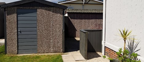 Ein Wohnhaus mit einer kleinen Gartenhütte, einem gepflasterten Weg und einem Blumentopf.