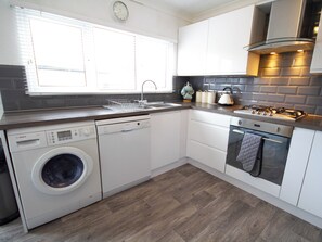 A modern kitchen with a Bosch dishwasher, a built-in oven, and a stainless steel range hood.