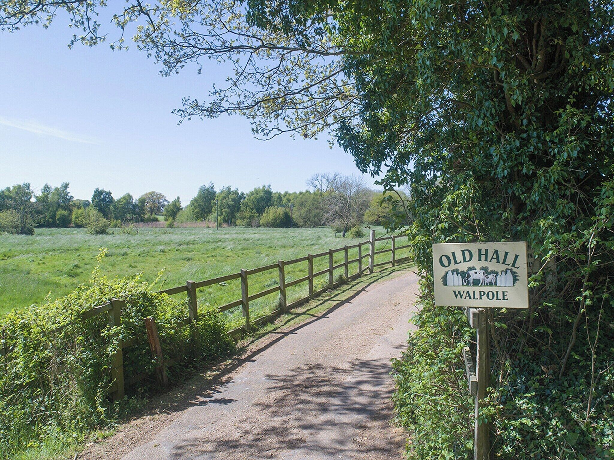 A sign for Old Hall in Walpole, with a pathway leading through a green field.