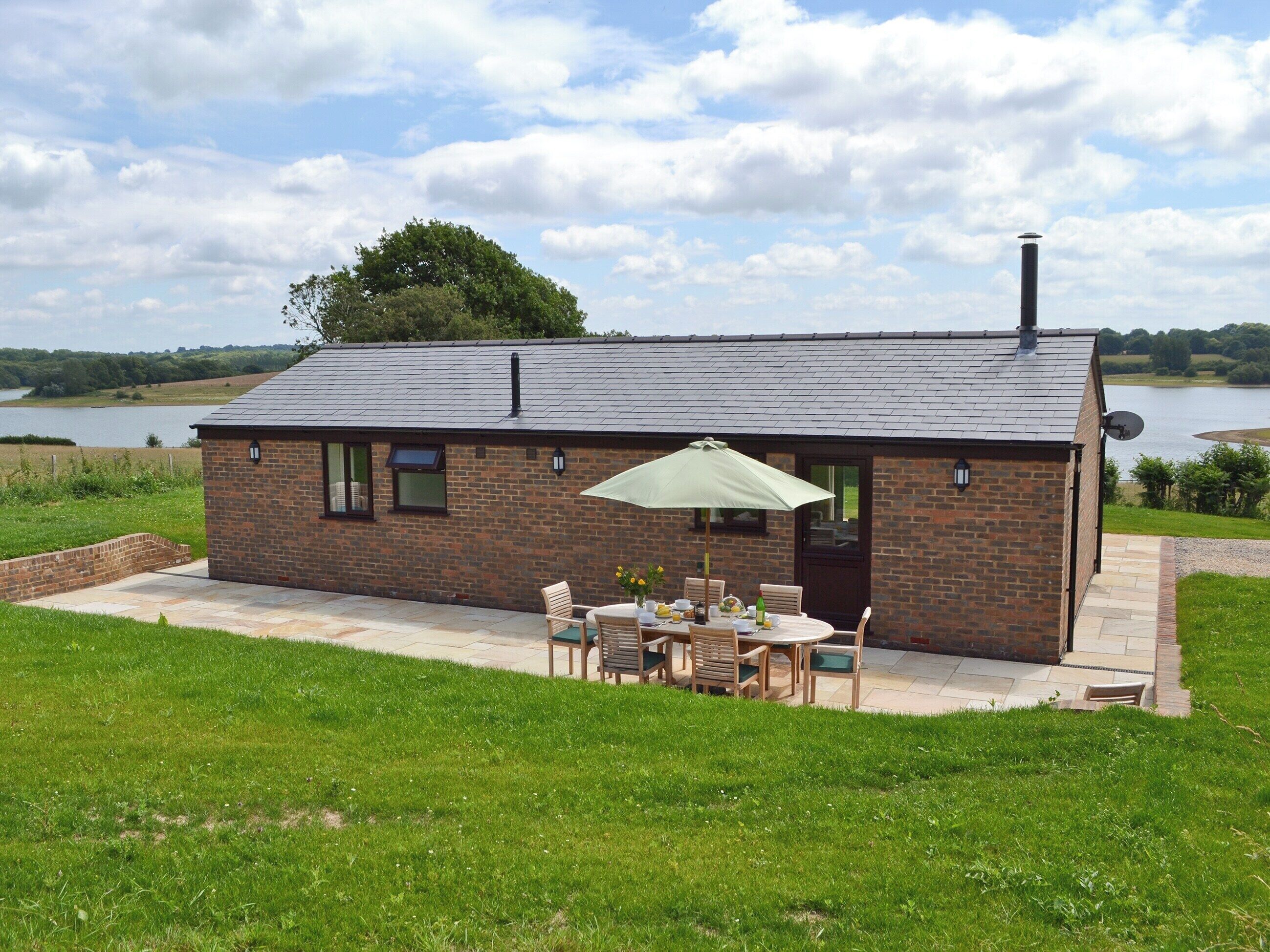 A small brick house with a patio, a table with chairs, and a large umbrella.