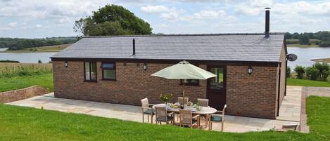 A small brick house with a patio, a table with chairs, and a large umbrella.