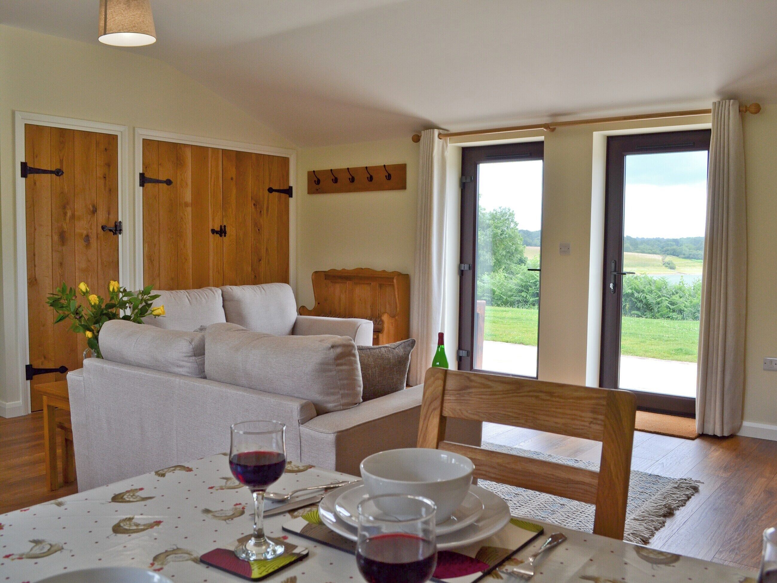 A dining area with a table set for two, a sofa, and a view of the outdoors.