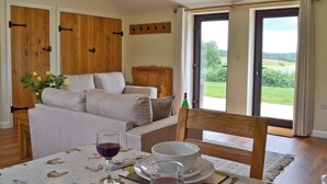 A dining area with a table set for two, a sofa, and a view of the outdoors. - 2 bedroom accommodation in Wadhurst, near Tunbridge Wells (Wadhurst, near Tunbridge Wells)