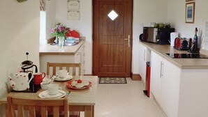 A compact kitchen with a wooden door, a coffee maker, a microwave, and a toaster. - A well-appointed, single storey cottage, close to the pretty village of St. (St Merryn, near Padstow)