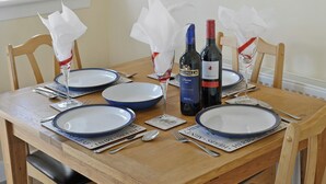 Een eettafel gedekt met blauwe borden, wijnflessen en servetten.