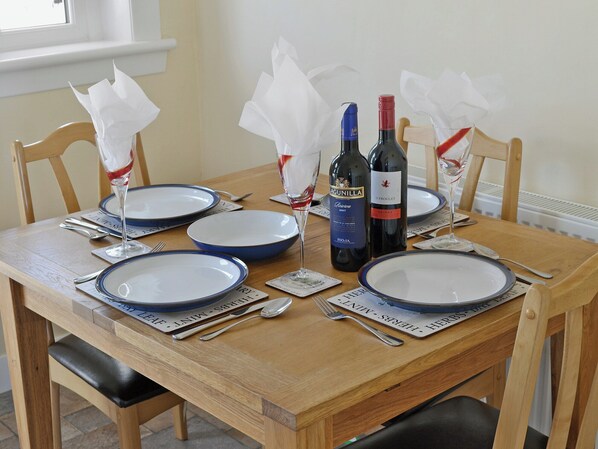 Een eettafel gedekt met blauwe borden, wijnflessen en servetten.