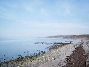 A coastal beach with pebbles and a clear view of the sea.