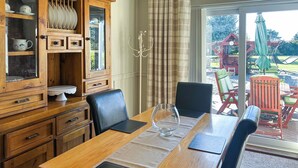 Un comedor con mesa de madera, sillas y vista al patio exterior.