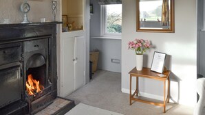 A cozy living room with a fireplace, a window with a view, and a small table with a vase of flowers. - 1 bedroom accommodation in Fraisthorpe, near Bridlington (Fraisthorpe, near Bridlington)