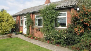 A brick house with a tiled roof, two windows, a door, and a chimney. - 1 bedroom accommodation in Fraisthorpe, near Bridlington (Fraisthorpe, near Bridlington)