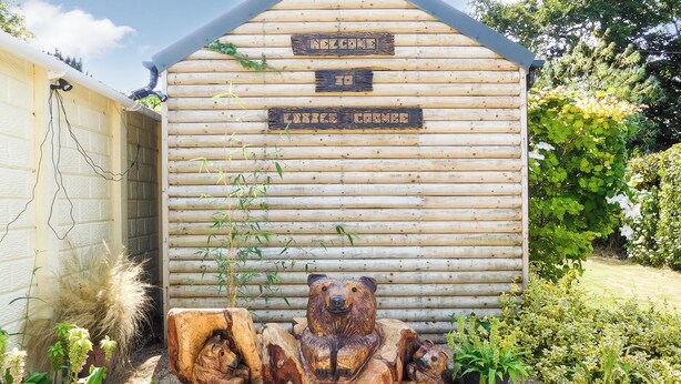 Een houten chalet met een beerbeeld er voor.