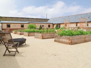 A rustic wooden cabin with raised garden beds, a wooden chair, and a grill.