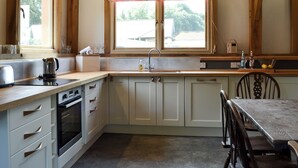 Una cucina con travi in legno, un lavello, un fornello e un tavolo da pranzo con sedie.