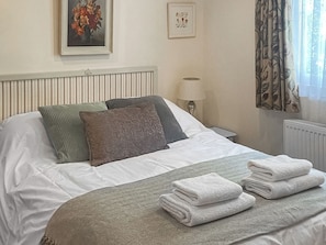 A neatly made bed with pillows, a bedside lamp, and a framed picture on the wall.