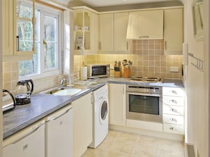 A compact kitchen with a dishwasher, oven, microwave, and a sink.