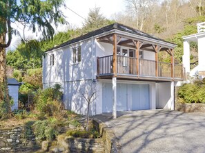 A two-story house with a balcony, a garage, and a stone wall. - 1 bedroom accommodation in Polperro, near Looe (Polperro, near Looe)