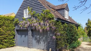 A two-story house with a dark wooden exterior, a sloped roof, and a garage door. - 1 bedroom accommodation in Mickleton, near Chipping Campden (Mickleton, near Chipping Campden)
