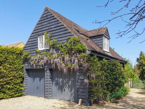 A two-story house with a dark wooden exterior, a sloped roof, and a garage door. - 1 bedroom accommodation in Mickleton, near Chipping Campden (Mickleton, near Chipping Campden)
