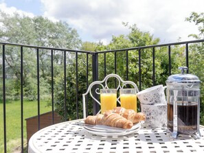 A table with croissants, juice, a coffee pot, and a teapot on a balcony with a metal railing and greenery in the background. - 1 bedroom accommodation in Mickleton, near Chipping Campden (Mickleton, near Chipping Campden)