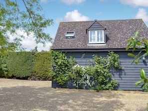 A house with a sloped roof, a small dormer window, and a gravel driveway.