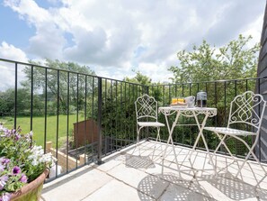 A balcony with a table and chairs, a potted plant, and a view of a green landscape. - 1 bedroom accommodation in Mickleton, near Chipping Campden (Mickleton, near Chipping Campden)