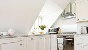 A kitchen with white cabinets, a microwave, a stove, and a window with a view. - 1 bedroom accommodation in Mickleton, near Chipping Campden (Mickleton, near Chipping Campden)