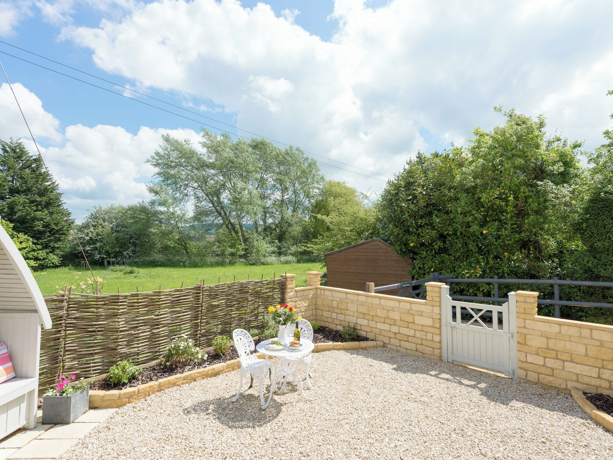 A patio with a table and chairs, a wooden fence, and a garden area.