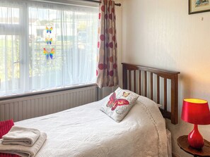 A bedroom with a bed, a window with curtains, a red lamp, and a view of the outside. - 2 bedroom accommodation in Balwest, near Marazion (Balwest, near Marazion)