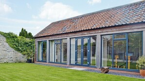 A modern house with a tiled roof, large glass windows, and a well-maintained lawn. - 1 bedroom accommodation in Moorlinch, near Bridgwater (Moorlinch, near Bridgwater)