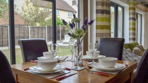 A dining table set for two with white plates, bowls, and cutlery, and a vase with purple flowers. - 1 bedroom accommodation in Moorlinch, near Bridgwater (Moorlinch, near Bridgwater)