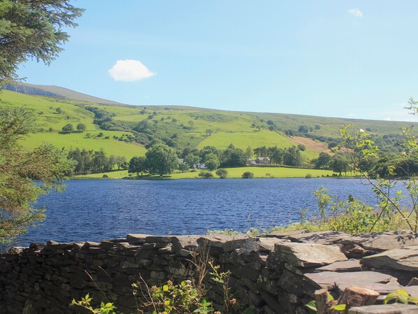 A stone wall, a body of water, and a green landscape with hills.