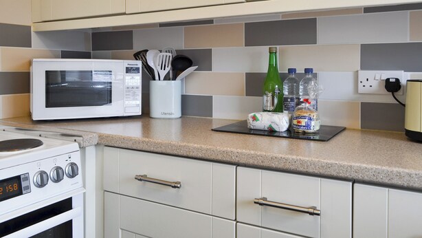 Eine Küche mit Mikrowelle, Backofen und einem Utensilienhalter.