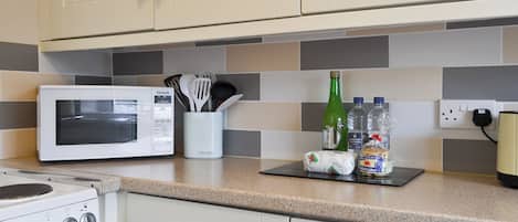 A kitchen with a microwave, oven, and a set of utensils in a holder.