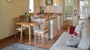 Une cuisine moderne avec des meubles en bois, un îlot central et un coin repas comprenant une table et des chaises.