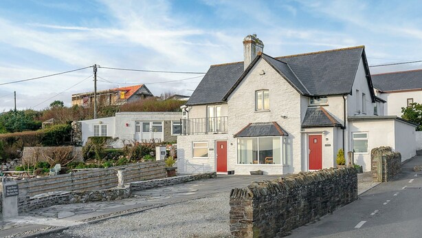 Une maison à deux étages avec un mur en pierre et une porte rouge.