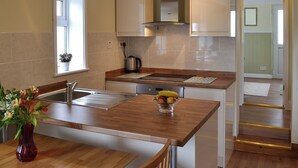 Une cuisine moderne dotée de plans de travail en bois, d’appareils électroménagers en acier inoxydable et d’une fenêtre laissant entrer la lumière naturelle.